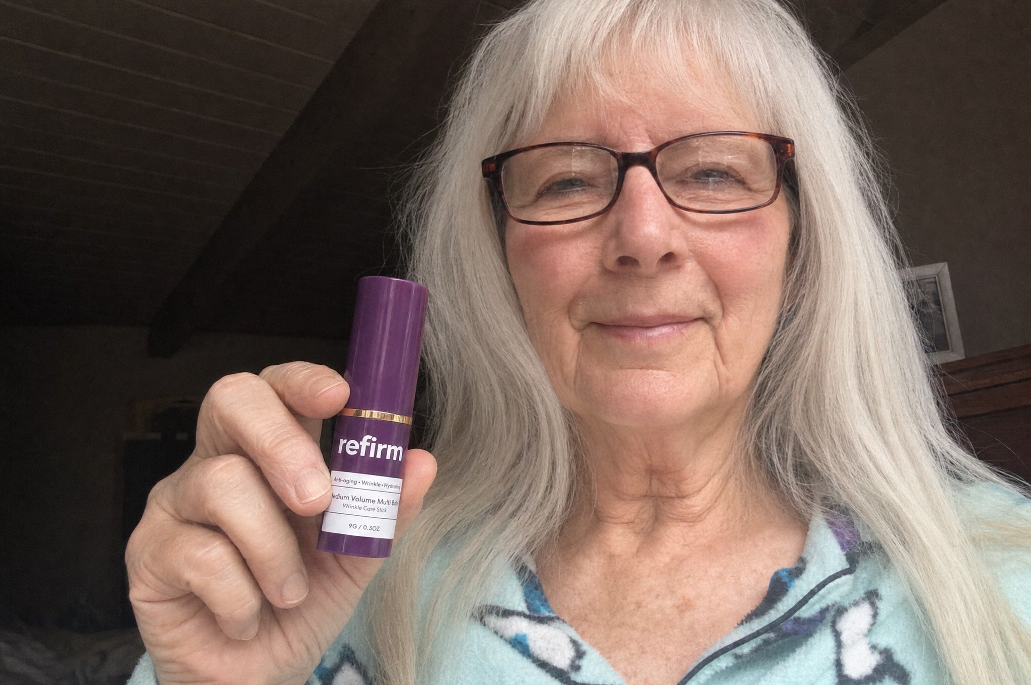 Woman in her 60s holding the balm, smiling