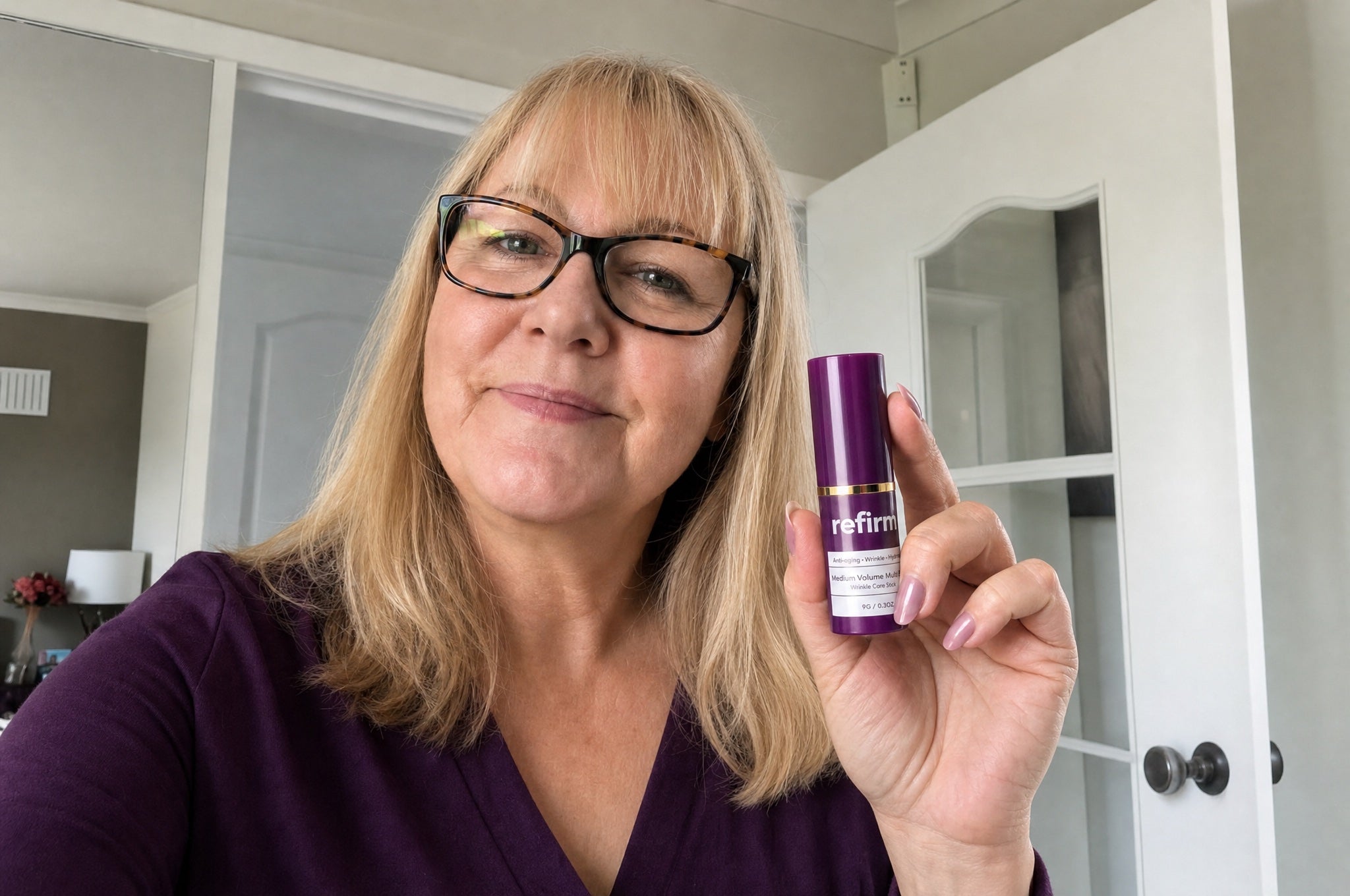 Woman on couch holding Refirm Calcium Balm proudly, big smile