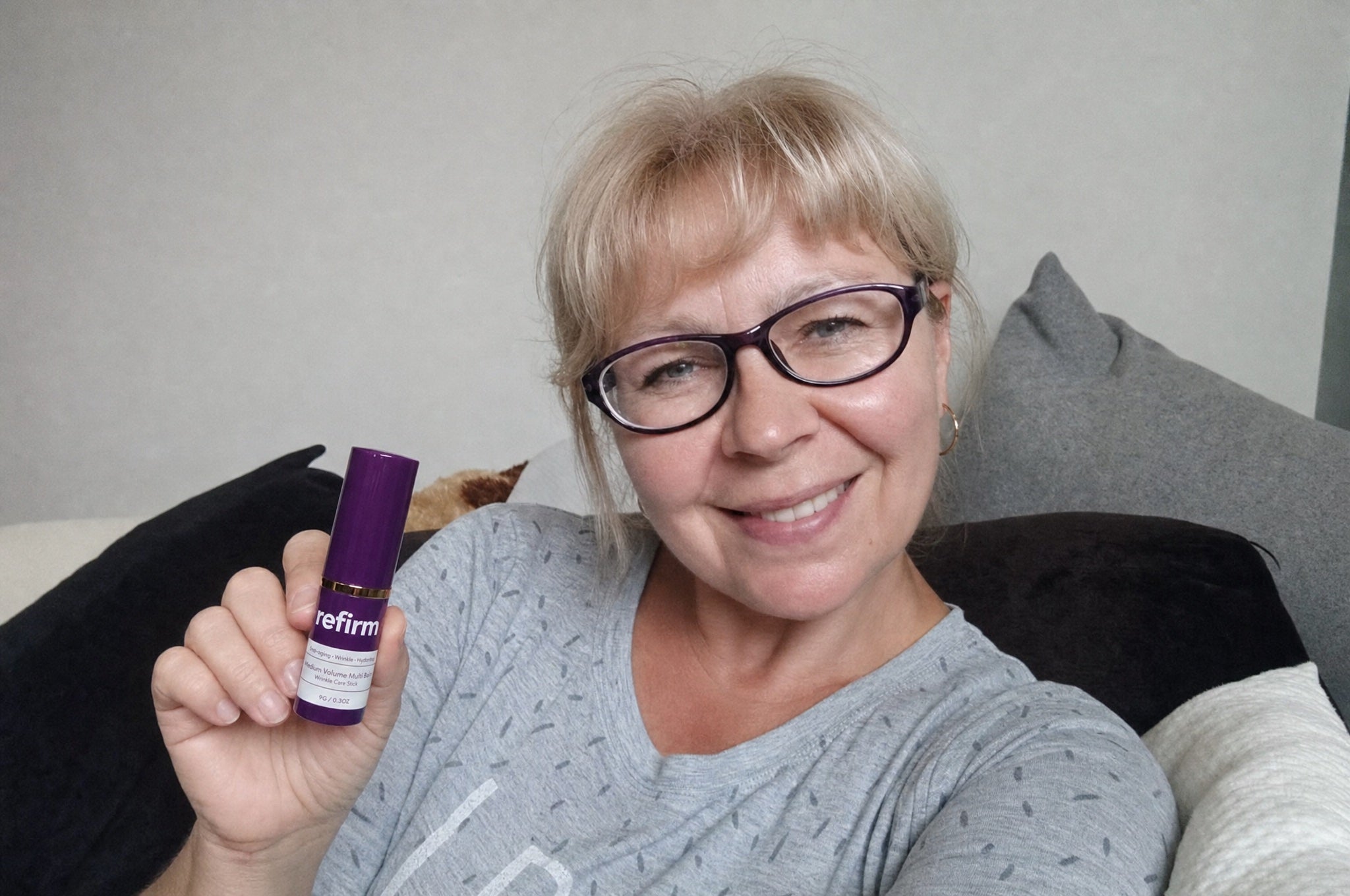 Woman holding Refirm Calcium Balm at jawline, composed smile